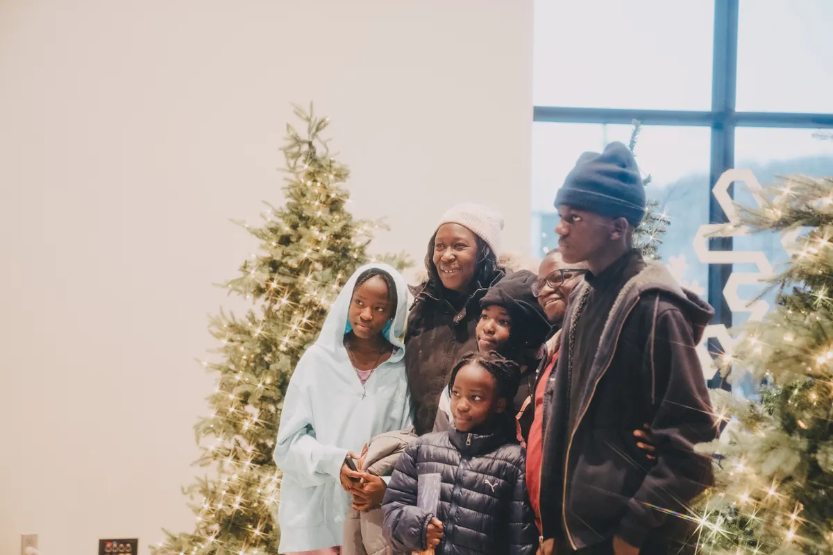 A family gathers by the lit Christmas tree in the lobby.