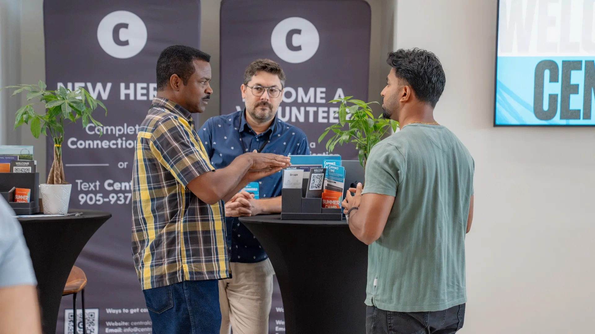 Three people talking at the Connections wall in the lobby.