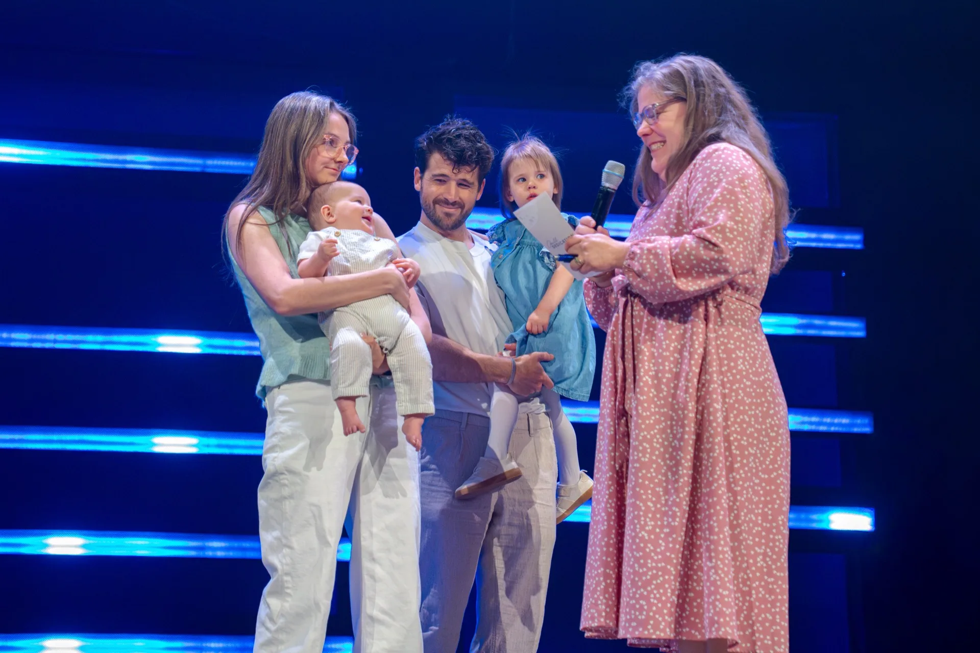 A family with two young children standing on stage during a child dedication.