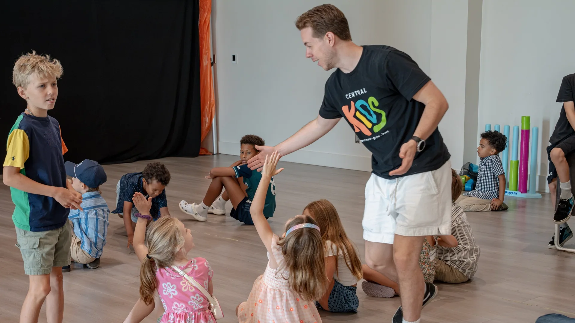 A Central Kids leader high-fiving a child in the kids area.